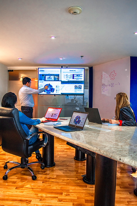 Instructor de SAC-WALABI exponiendo ideas en un monitor a dos trabajadores, simbolizando asesoría y consultoría tecnológica.